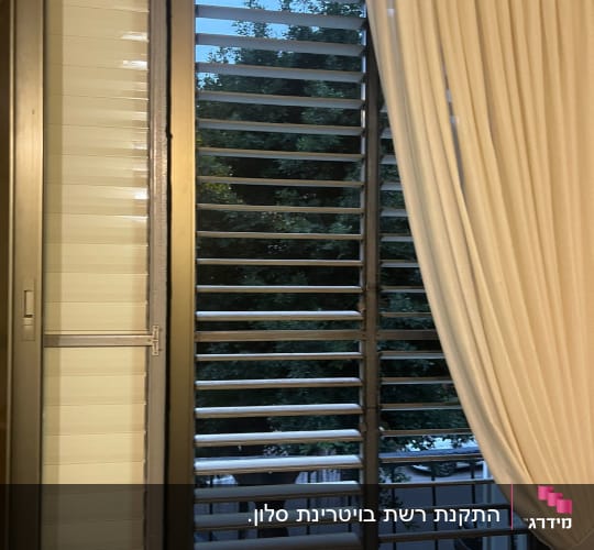 תריסי אלומיניום בחלון עם וילון לבן